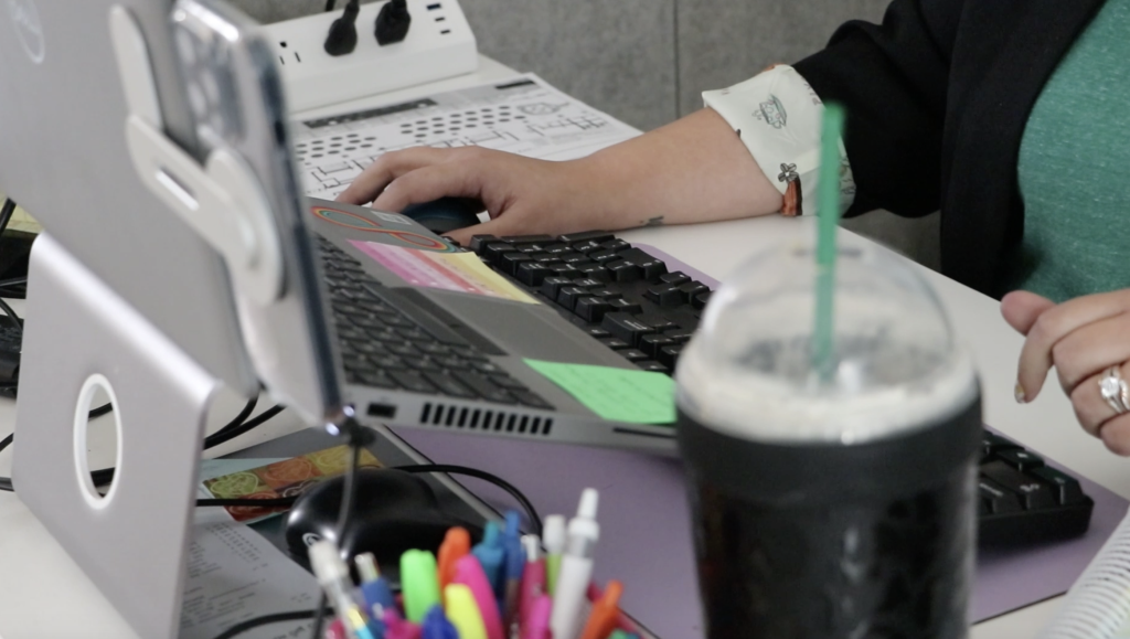 a woman's desk with her hand using the mouse of her computer while working at the Orange County Rape Crisis Center