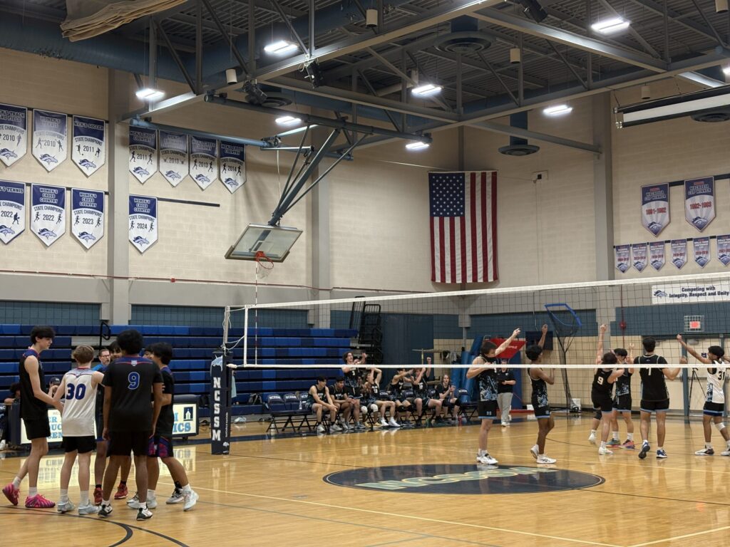 North Carolina School of Science and Mathematics boys volleyball team plays against Triangle Math and Science Academy boys volleyball team in a high school gym.