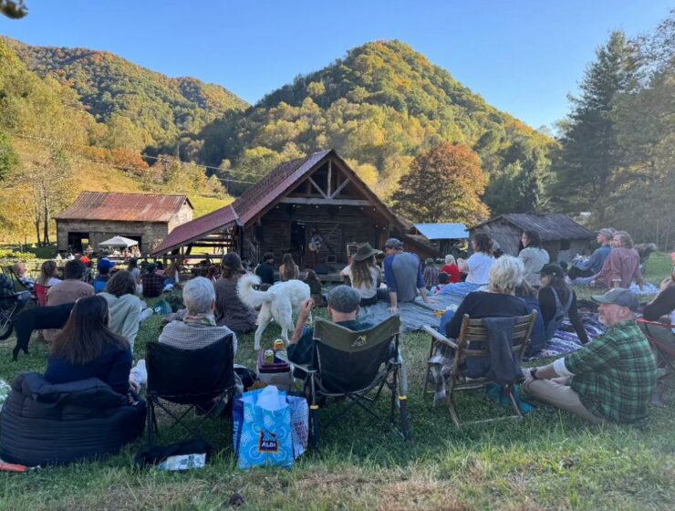 Community members, surrounded by green mountains, gather in front of a barn for the Straight to Love event at Rare Bird Farm.