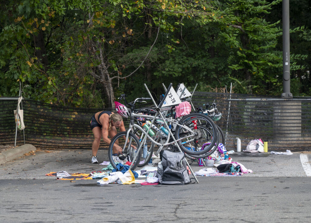 An athlete rushes into the transition zone during the She Tris triathlon to shift from cycling to running, a critical moment that could make or break their race. Known as the “fourth discipline” of triathlon, transitions demand focus and efficiency under pressure.